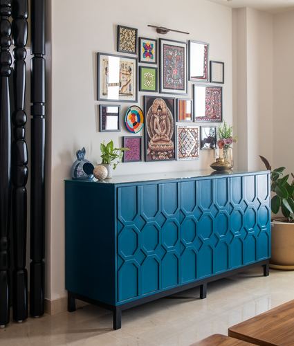 Teal geometric-front sideboard beneath a gallery wall of framed Indian art