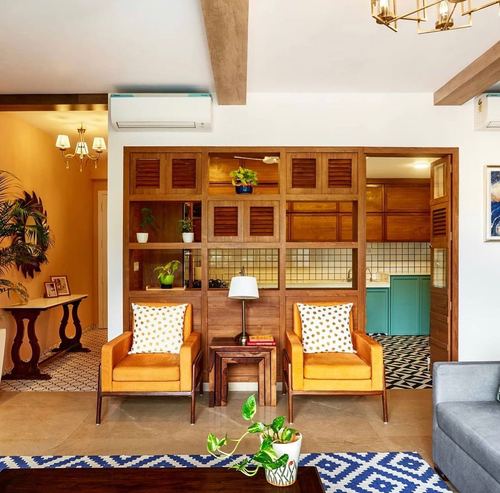 Living room with orange leather chairs facing a wooden shutter divider wall opening to a teal kitchen