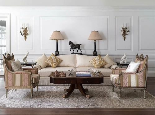 Symmetrical cream living room with striped armchairs, gold pillows, and a dark wood coffee table