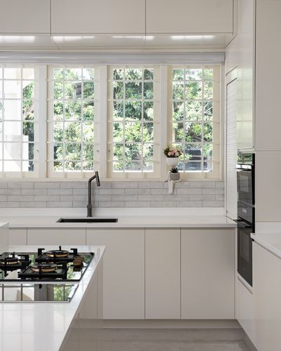 White minimalist kitchen with grid windows overlooking greenery, black faucet, and tiled backsplash