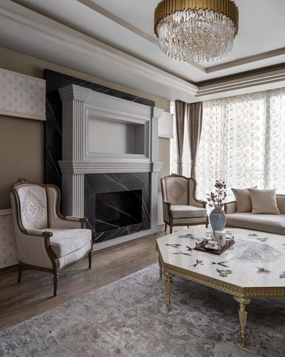 Classical living room with marble fireplace, crystal chandelier, and gilded octagonal coffee table