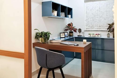 Small study nook with wood desk, grey chair, and navy blue wall cabinets