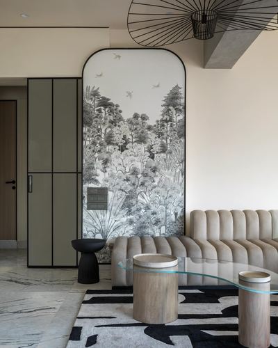 Living room with arched forest mural, channel-tufted sofa, and glass coffee table on marble floor