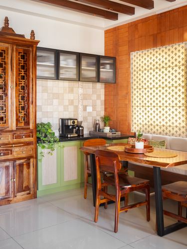 Kitchen with carved wooden cabinet, green cabinetry, tiled backsplash, and live-edge wood dining table