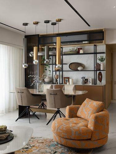 Dining area with brass pendant lights, marble-backed shelving, and an orange boucle swivel chair in foreground