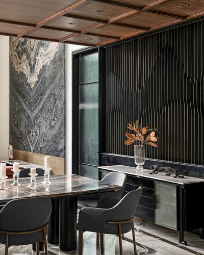 Dining room with marble slab wall, coffered wood ceiling, and rippled metal panel behind marble console