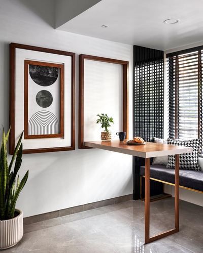 Dining nook with framed wall art, wooden table, and striped blinds by window