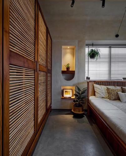 Bedroom with ribbed wood wardrobe, lit wall niche, hanging plant and cane-detailed daybed