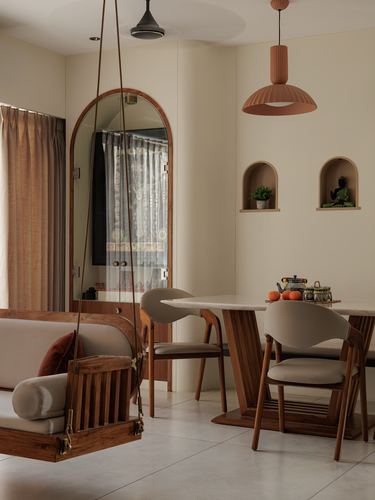 Dining nook with wooden swing, arched mirror, and terracotta pendant lights over a marble table
