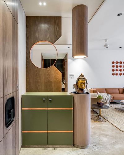 Foyer with fluted column, brass buddha bust, round mirror over green cabinet