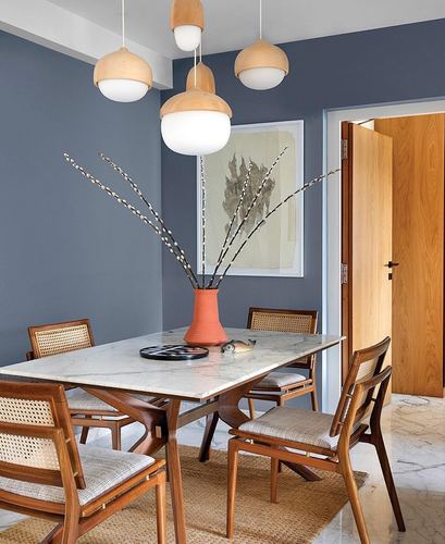 Dining room with marble-top wood table, cane chairs, globe pendant lights, terracotta vase with branches
