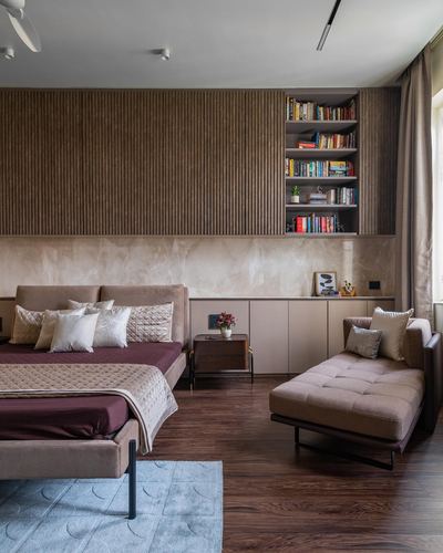 Bedroom with fluted wood wall, built-in bookshelf, maroon bed and tufted chaise lounge