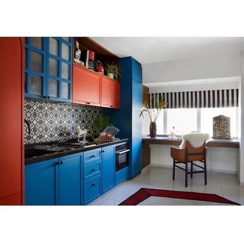 Blue and orange kitchen with patterned tile backsplash and window seat desk beyond