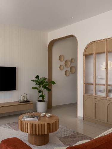 Living room with arched niche, fluted wood coffee table, glass cabinet and wall-mounted plates