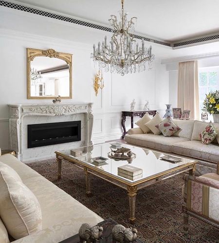 Formal living room with marble fireplace, gilt mirror, crystal chandelier and mirrored coffee table