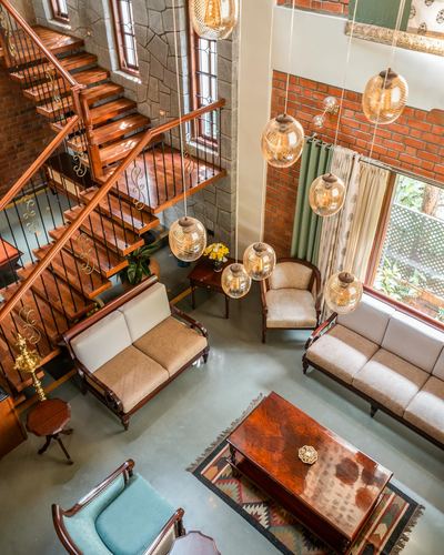 Overhead view of a double-height living room with wooden staircase and hanging globe lights