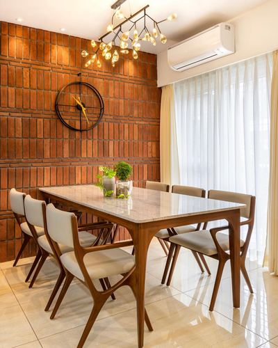 Dining room with marble-top wood table, sculptural chairs, and exposed brick wall with round clock