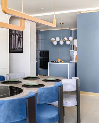 Blue-toned kitchen and dining area with globe chandelier and velvet chairs