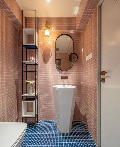 Pink-tiled bathroom with pedestal sink, oval mirror, and blue mosaic floor