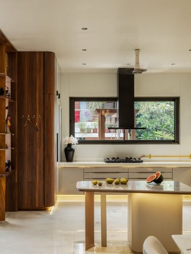 Modern kitchen with curved wood cabinet, marble island, black hood, and window view of greenery