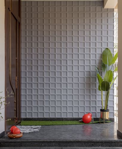 Foyer with gridded grey panel wall, wooden door, turf strip, and red decorative spheres