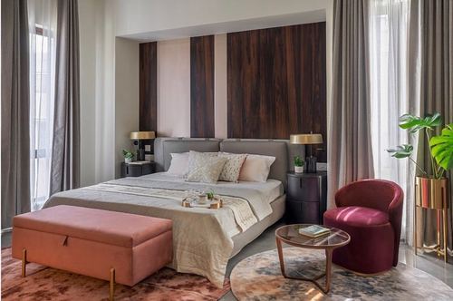 Bedroom with striped wood veneer headboard, coral bench, and maroon velvet chair