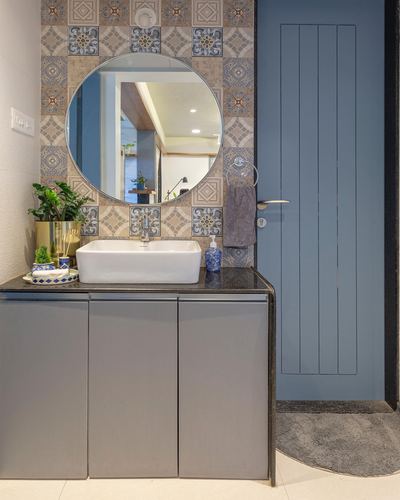 Bathroom vanity with patterned tile wall, round mirror, vessel sink and blue paneled door