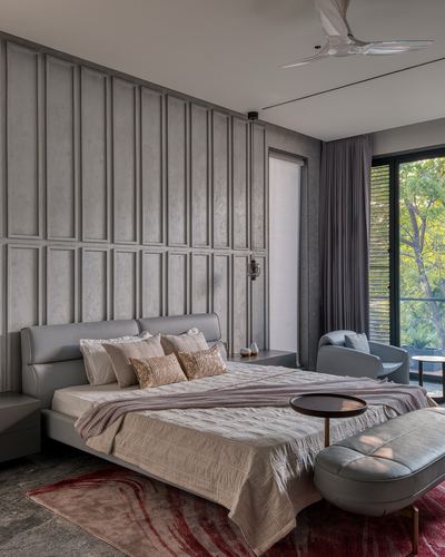 Grey paneled bedroom with upholstered bed, leather bench, and garden-facing glass wall