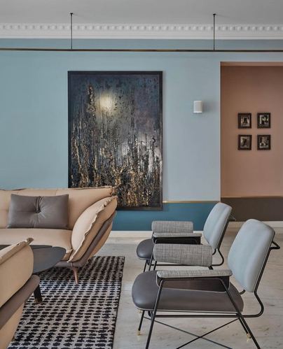 Blue and peach color-blocked living room with abstract art and mid-century style chairs