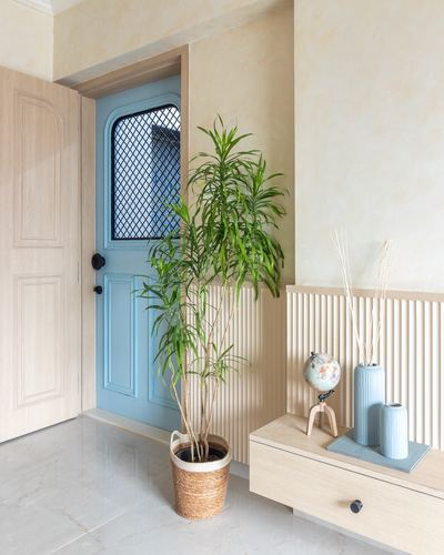Entryway with blue arched fluted door, potted plant, and pastel console with vases and globe