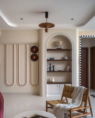 Arched niche with wood shelves beside curved plaster wall and cane lounge chair