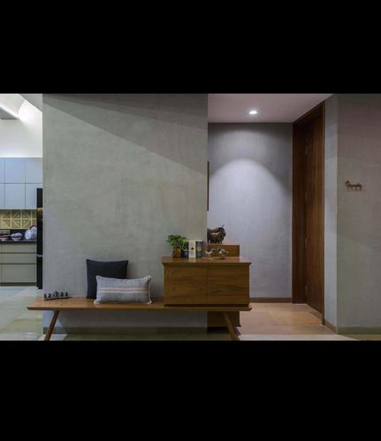 Entryway with wooden bench, console table, and spotlit textured wall beside dark wood door