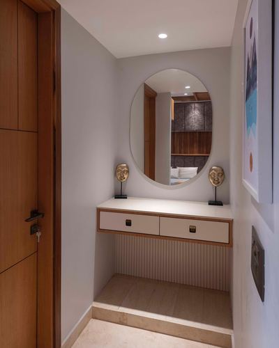 Foyer with oval mirror above a floating console flanked by gold face sculptures, wooden door alongside