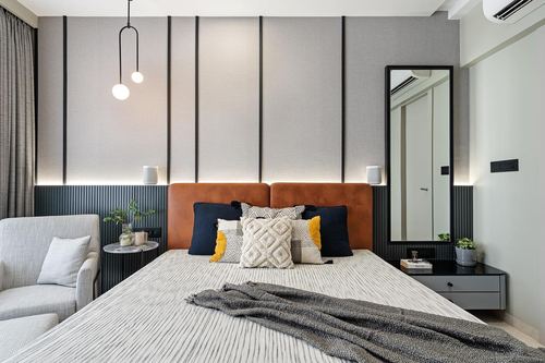Bedroom with tan leather headboard, fluted grey panelling, mirror and cove lighting