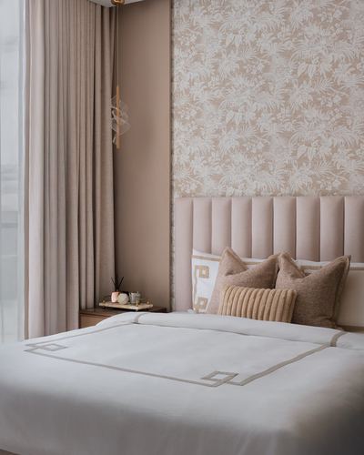 Blush bedroom with tufted headboard, floral wallpaper, and white embroidered bedding beside a curtained window