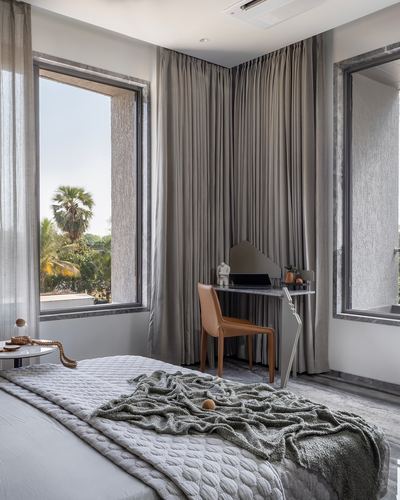 Bedroom corner with sheer curtains, marble-top desk, leather chair, and palm tree view