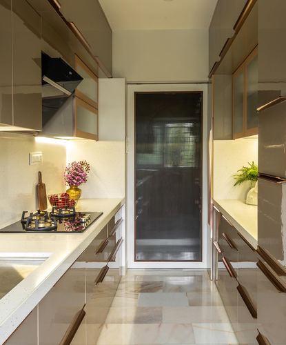 Galley kitchen with bronze-toned cabinetry, stone counters and a fluted glass door at the end