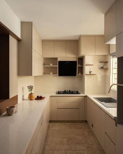 Beige U-shaped kitchen with stone countertops, black built-in oven, and open display shelves
