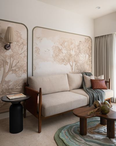 Living room sofa with leather sling frame against arched tree-mural wall panels, round wood coffee table in front