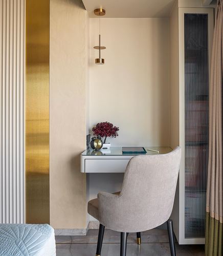 Small built-in desk nook with brass pendant light and striped upholstered chair in a bedroom corner