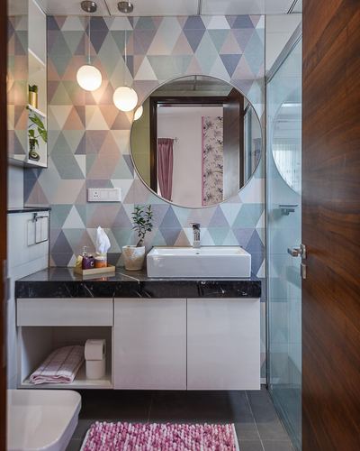 Bathroom vanity with round mirror, pastel triangle wallpaper, and dark marble countertop