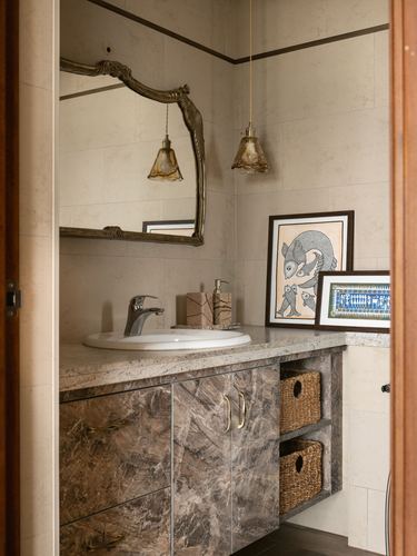 Bathroom vanity with marble counter, ornate mirror, two amber pendant lights, and wildlife artwork