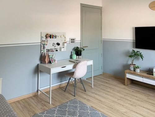 Small study nook with white desk, patterned chair, and pegboard against blue-and-cream two-tone wall