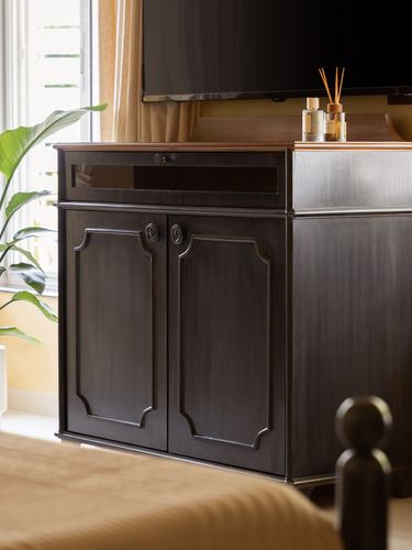 Dark wood paneled cabinet under mounted tv beside window plant and bed post
