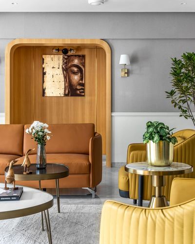 Living room with orange sofa in arched wood niche and mustard chairs around marble tables