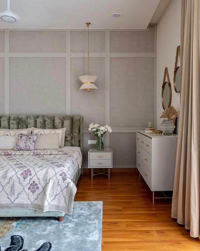 Bedroom with green velvet headboard, paneled walls, pendant light, and white chest of drawers