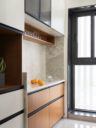 Kitchen counter with oranges, stone backsplash, wood cabinetry and black-framed window