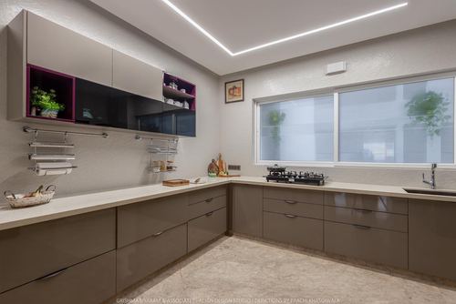 L-shaped modern kitchen with glossy taupe cabinets, magenta-accented open shelving, and large window