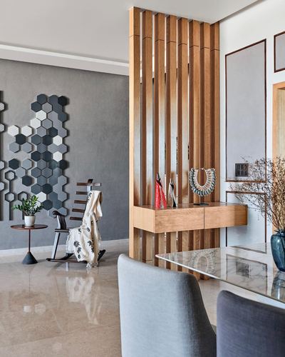 Foyer with wood slat screen, floating console, and hexagonal mirror wall beside dining area