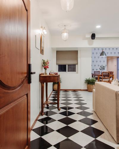 Entry hallway with wooden door, console table, and black-and-white checkerboard marble floor leading to living room